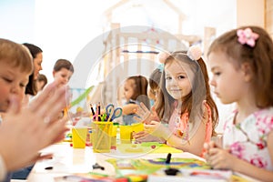 Kindergarten kids doing arts and crafts with teacher in day care centre photo