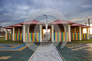 Kindergarten playground with bright new alcove with multicolored low fence, big yard with soft rubber flooring on blue sky copy