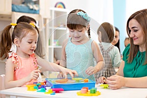 Kindergarten teacher and children playing toy sorter in daycare centre photo