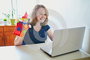 Kindergarten teacher in front of laptop having video conference chat with children