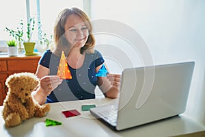 Kindergarten teacher in front of laptop having video conference chat with children