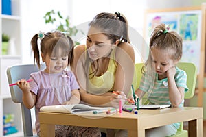 Kindergarten teacher helping children in artclass