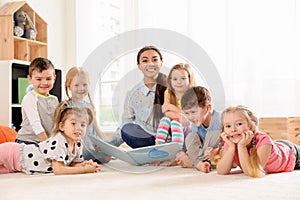 Kindergarten teacher reading book to children indoors