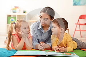 Kindergarten teacher reading book to children. Learning and playing