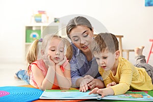 Kindergarten teacher reading book to children. Learning and playing