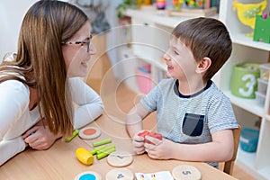 Kindergarten Teacher Supports Cute Boy in Educational Game Play photo