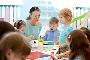 Kindergartener teaches kids handcraft at nursery or playschool