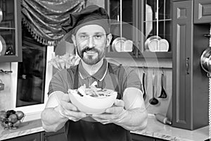 Kindhearted pleased cook offering a bowl of vitaminic salad