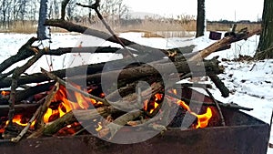 Kindling a brazier with tree branches in a snowy forest.