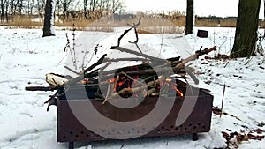 Kindling a brazier with tree branches in a snowy forest.