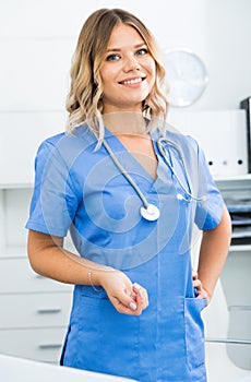 Kindly woman in doctor`s uniform greets visitors at modern office