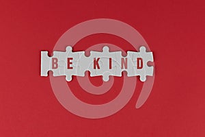 Kindness inspirational words - Be kind. With text on white puzzle jigsaw on red background. Humanity concept.
