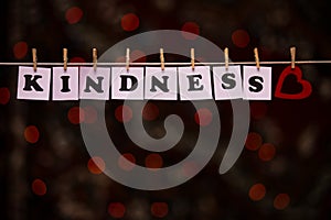 Kindness text on papers with clothespins with garland bokeh on background