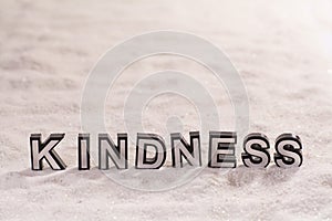 Kindness word on white sand