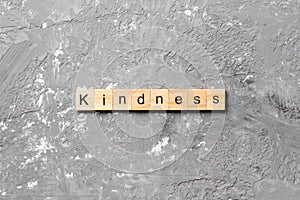 Kindness word written on wood block. kindness text on table, concept