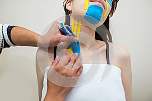Kinesio taping. The physiotherapist applies kinesiology tape to the patient`s neck. Post-traumatic rehabilitation
