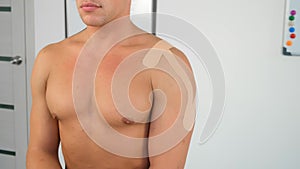 Kinesiology tapes on man's shoulder and hand for fixation of muscles, closeup.