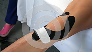 Kinesiology tapes on woman's leg to fix knee joint after injury, closeup view.