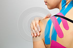 Kinesiotaping, kinesiology. Female athlete with kinesiotape, muscle tape on shoulder photo