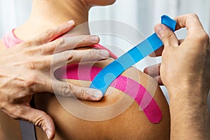 Kinesiotaping - physiotherapist taping injured patient shoulder with kinesio tape