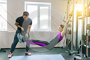 Kinesis technology, kinesitherapy, healthy lifestyle. Young woman doing rehabilitation exercises with personal instructor using