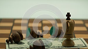 King chess piece and pawns on a dollar banknote on a chess board