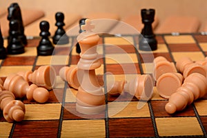 King figure on chessboard with pawns laying down Winning concept