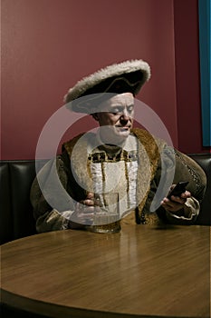 King Henry VIII using mobile phone at table photo