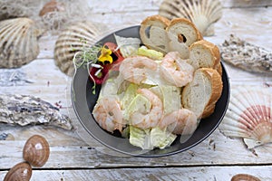 King prawn salad. Marine composition with a bowl of shrimp salad with iceberg lettuce, on a white wood table, top view.