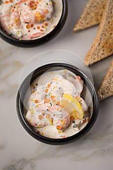 King prawn shrimps salad with orange salmon Keta caviar roe, herbs, lemon zest, cream and whole grain toast bread in black