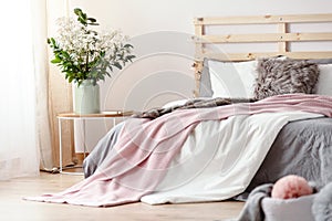 King-size bed with grey sheets and pink blanket standing in brig