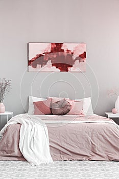 King size bed with pastel pink and white bedding in trendy bedroom