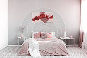 King size bed with pastel pink and white bedding in trendy bedroom interior