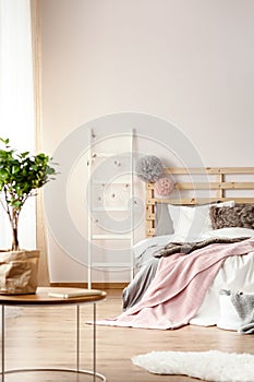 King-size bed with pink blanket, fur cushion and wooden bedhead photo