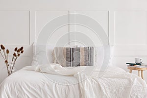 King size bed in white simple bedroom interior, real photo