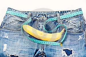 Kinky banana fruit on jeans crotch, close up.