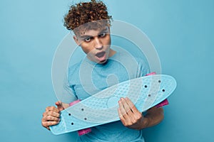 kinky guy skateboard in hand in blue t-shirts isolated background