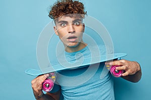 kinky guy skateboard in hand in blue t-shirts isolated background