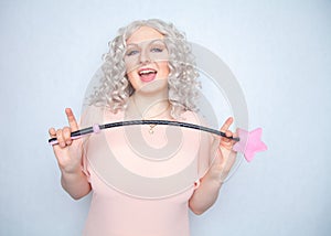 Kinky pretty woman with pink star riding crop. cute blonde woman holds bdsm whip on white solid studio background.