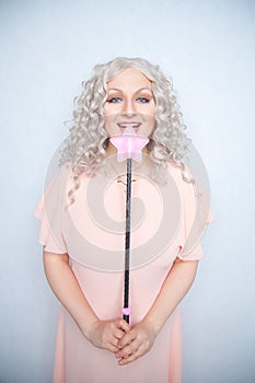 Kinky pretty woman with pink star riding crop. cute blonde woman holds bdsm whip on white solid studio background.