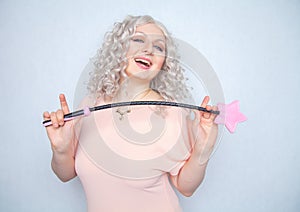 Kinky pretty woman with pink star riding crop. cute blonde woman holds bdsm whip on white solid studio background.