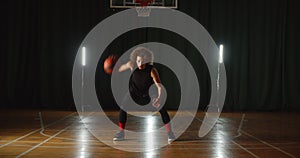 Kinky young caucasian basketball player dribbling training ball tricks neon light background