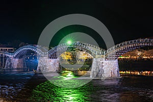 Kintai Bridge Illuminated at night. Cherry blossoms along the Nishiki River bank. Iwakuni, Yamaguchi Prefecture, Japan.