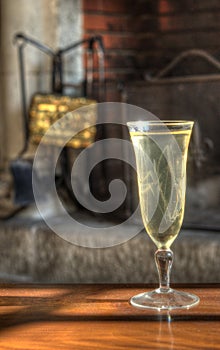 Kir glass on a wooden table in front of a French vintage fire place.