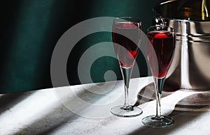 Kir Royale alcoholic cocktail with blackcurrant liqueur, prosecco and cocktail cherry. Dark green background, hard light and