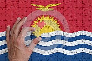 Kiribati flag is depicted on a puzzle, which the man`s hand completes to fold