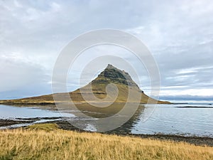 Kirkjufell in Iceland famous mountain reflecting in lake during cloudy day