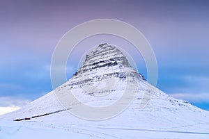 Kirkjufell mountain, Iceland. Winter natural landscape. The mountain ont he sky background. Snow and ice. photo
