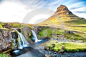 Kirkjufell Waterfalls and Mountain at sunset, wide angle view on a sunny summer day