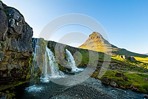 Kirkjufellsfoss waterfall and Kirkjufell mountain in sunny day